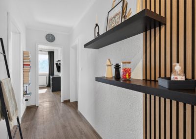 Flur mit Holzlamellenwand und schwarzem Wandregal in Kaarst